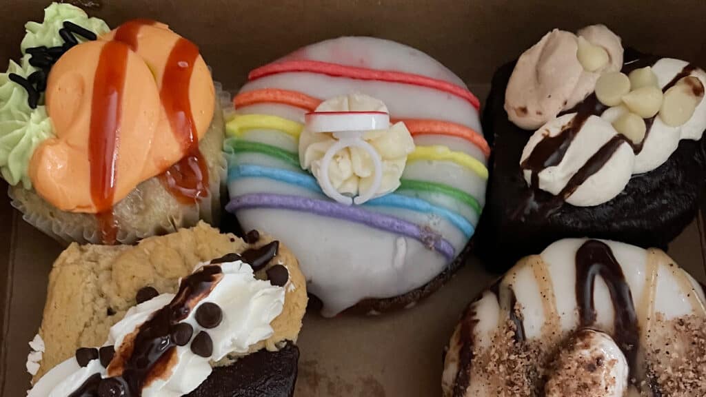 aerial view of a box of colorfully decorated cupcakes and donuts