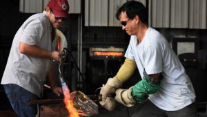 Photo of two artists bending glass with a torch