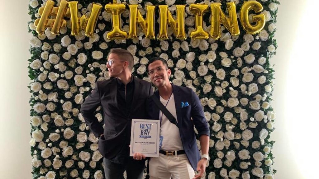 Photo of Best Blogger winners against a floral wall with an inflatable sign that reads "winning"
