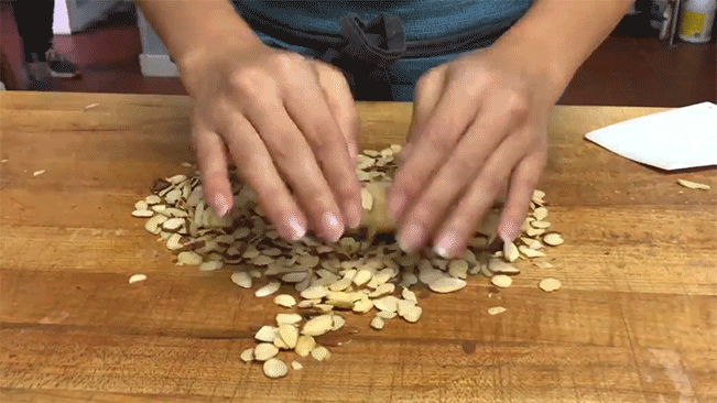 Pastry dough being rolled in crushed almonds 