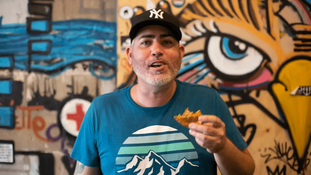 Photo of restaurant owner Ed Allen eating an empanada