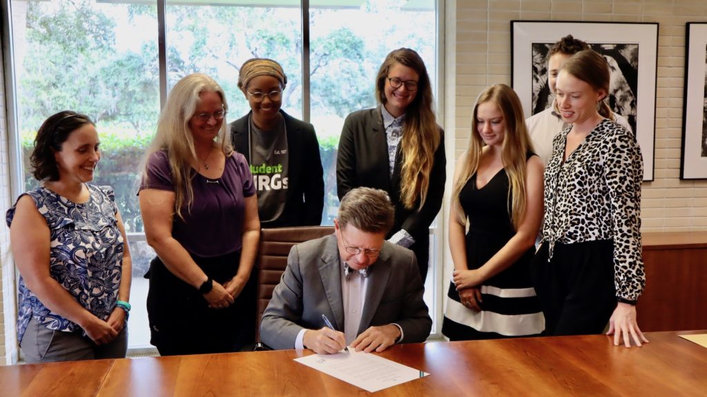 Eckerd College President signs pledge surrounded by students