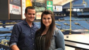 Restaurant owners pose in front of a baseball diamond