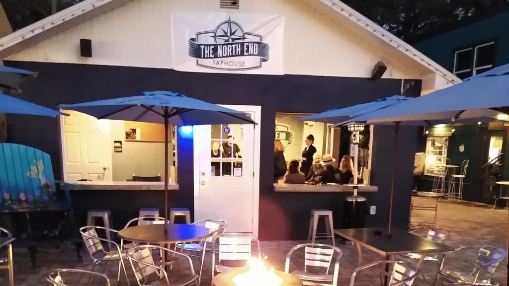 Exterior of a blue and white tap house with a fire pit out front