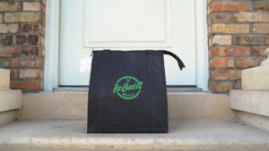 A Rebuilt Meals insulated delivery bag sitting on the doorstep of a home