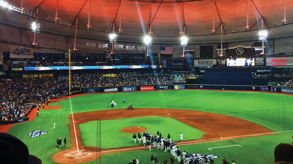 The inside of Tropicana Field, home of the baseball team the Tampa Bay Rays. Lit with orange ceiling and green grass after a game