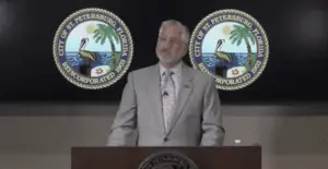 Mayor standing at a podium with a city sigil displaying behind him