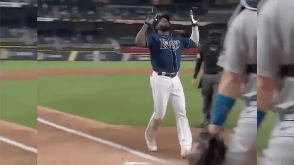 Image of Rays baseball player running to the plate with hands up in the air
