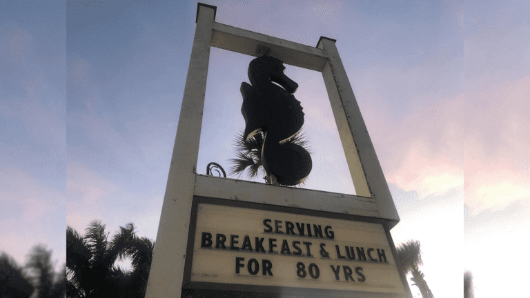 a tall sign with a sea horse figure carved out