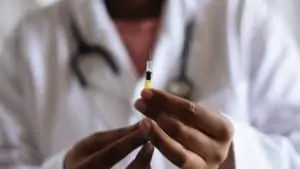 Photo of a doctor in a white coat holding a syringe