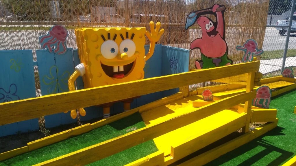 Two cartoon figures set in front of a ramp for a mini golf course