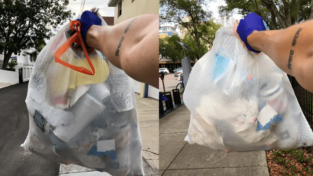 filled trash bags held out with a purple gloved hand