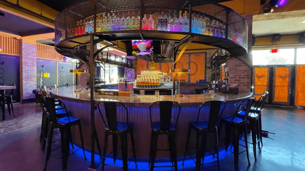 a circular bar with rainbow lights on the bottles over the bar