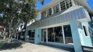 Exterior of a blue building with a pride flag in the window