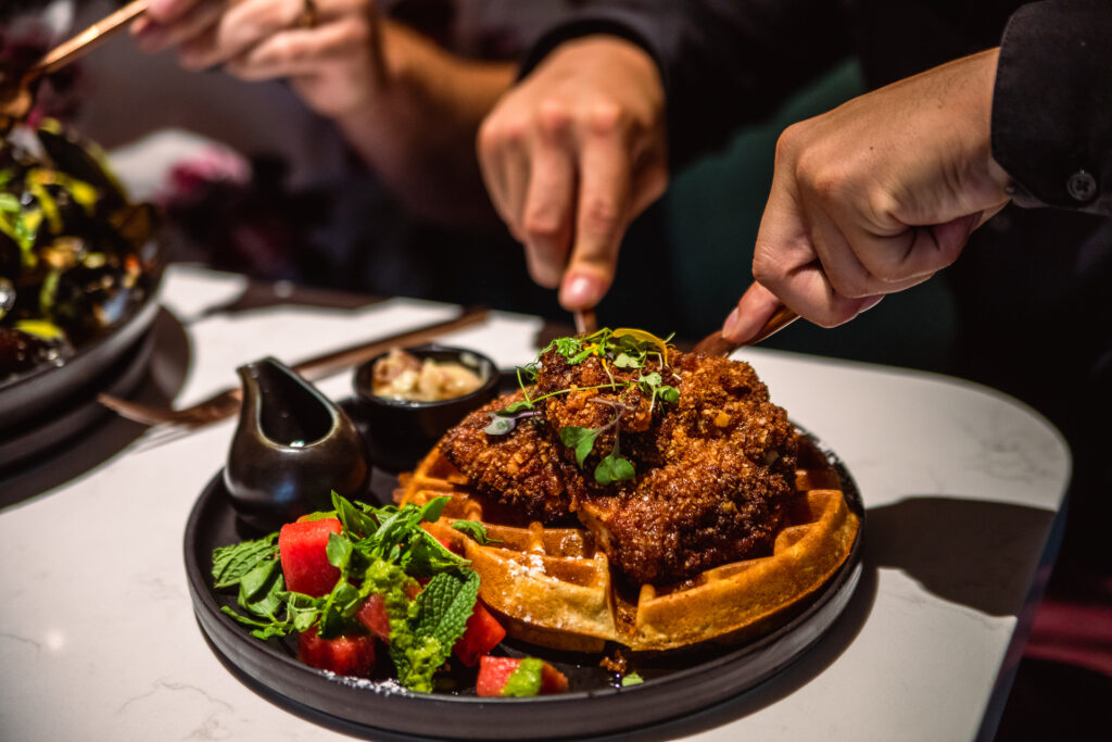Fried chicken and waffles on a large black plate