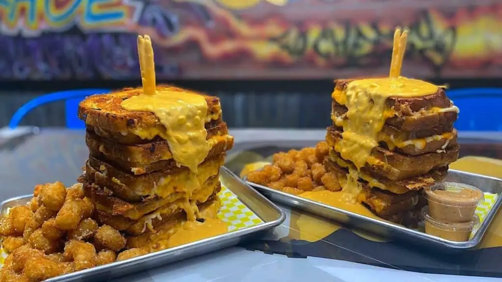 two large Fo' Cheezy grilled cheese dishes with tater tots and cheese overflowing