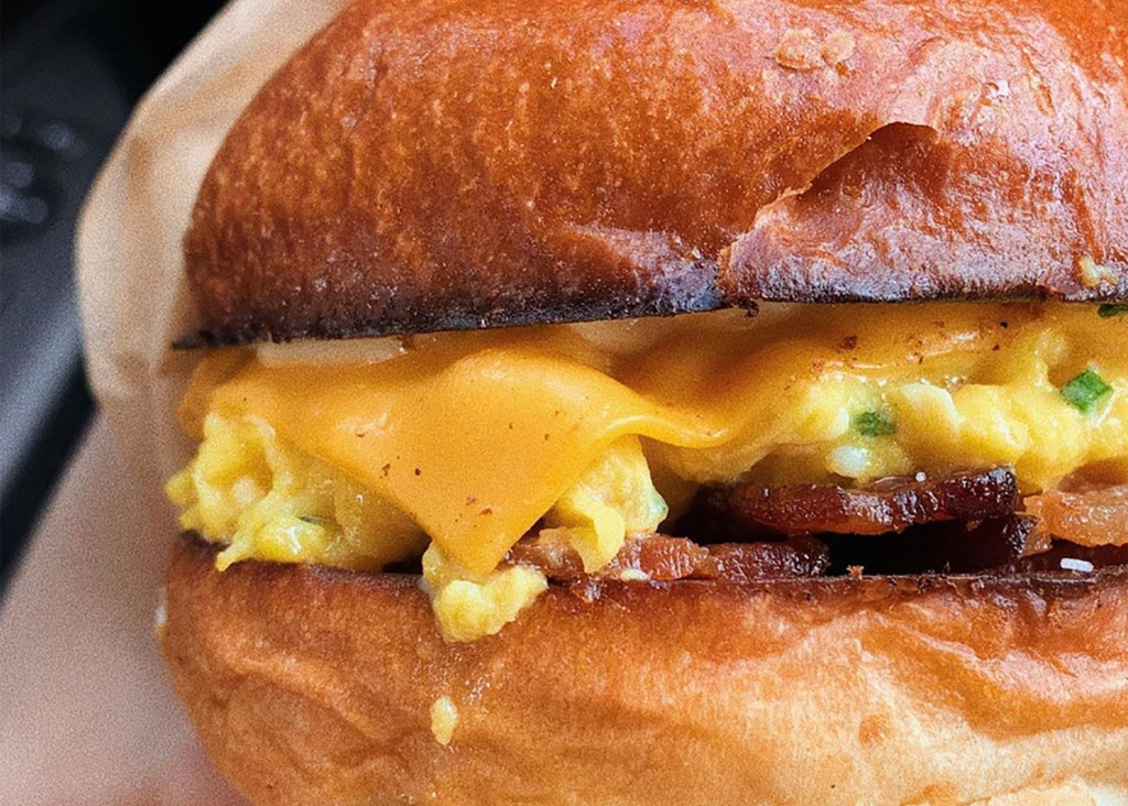 close up of a breakfast sandwich with melted cheese and bacon