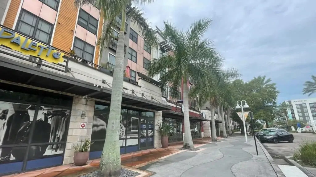 exterior of a brick building with a pedestrian walkway and palm trees out front