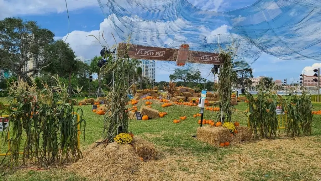 outdoor pumpkin patch with hay bails and a wooden archway