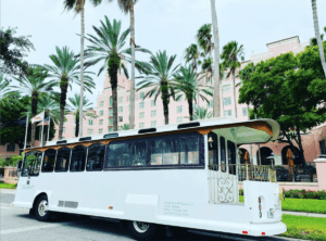 White trolley in front of pink hotel with palm trees