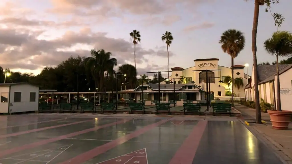 exterior of a shuffleboard club with rain on the courts and palm trees in the background