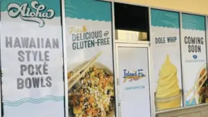 exterior of a restaurant with a giant coming soon sign in blue and white with images of soft serve ice cream and grain bowls on the front