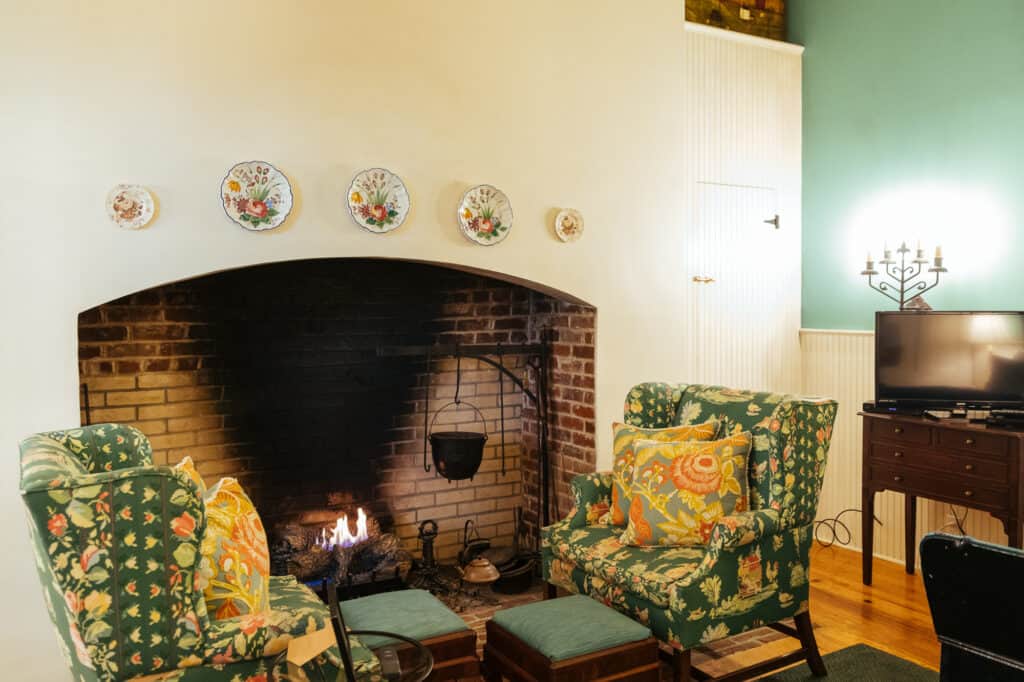 a fire place with two green chairs set in front of it