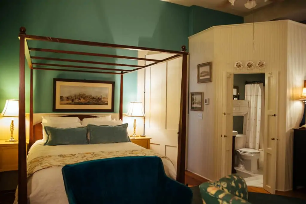 a large bedroom with a wooden frame and an open door leading to the bathroom