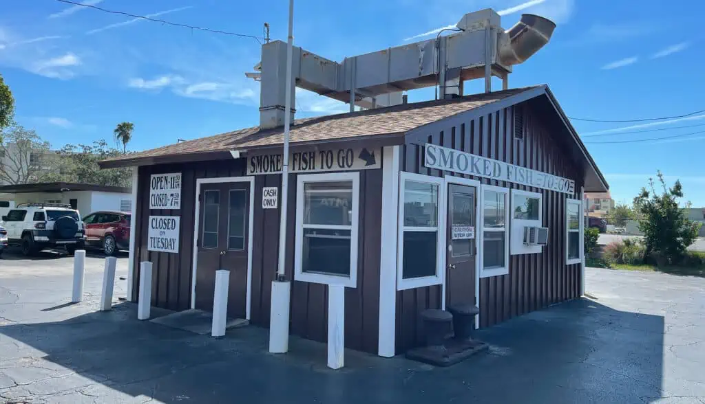 exterior of a fish shack with brown wooden walls in a parking lot
