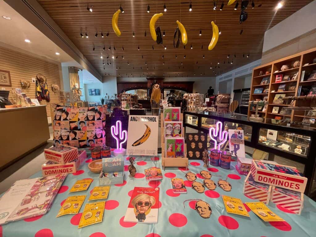 bananas hanging from the wall, with a display of neon cacti and enamel pins on a table. 
