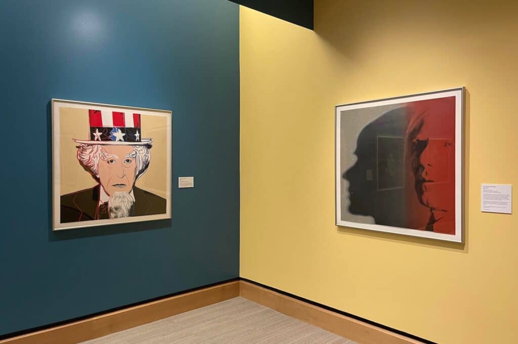 A photo of the same uncle next to a pop art photo of Andy Warhol on the wall. 