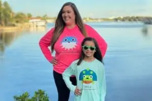 two people standing on the waterfront in a pink long sleeve shirt and a blue long sleeve shirt