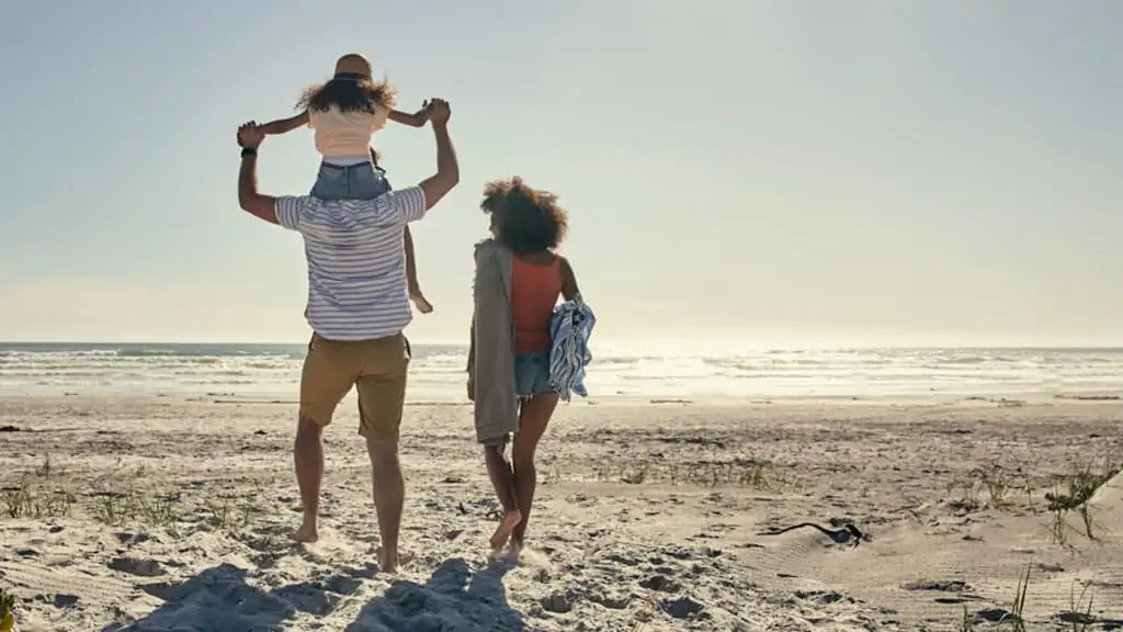 two parents with a child walking on the beach