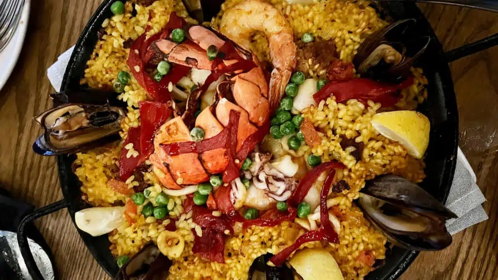 a large pan of paella with lobster tail and other seafood on top