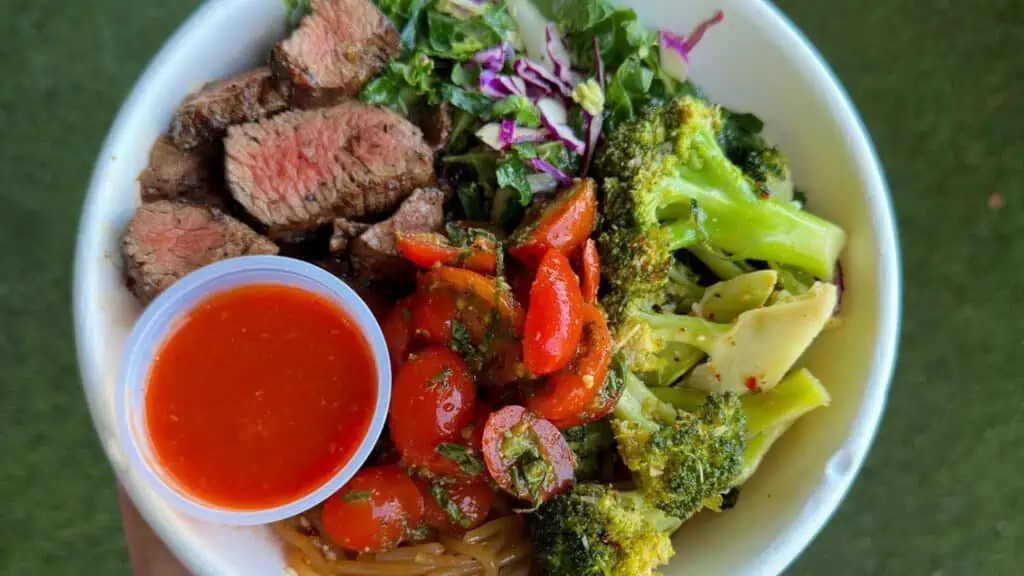 Overhead view of a bowl with steak, tomatoes, broccoli and more from fresh kitchen