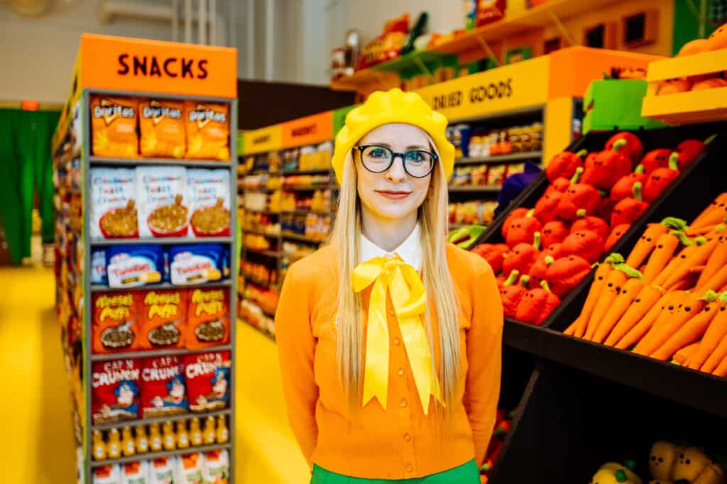 Lucy Sparrow stands inside Tampa Fresh Foods, her massive felt art installation at Water Street.