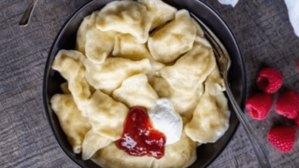 Aerial view of a plate of pierogi with a dollop of cheese at the center