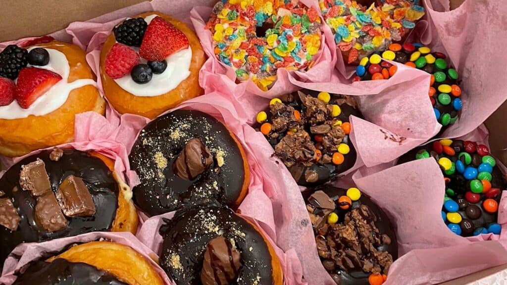 rows of chocolate frosted donuts in a pink box