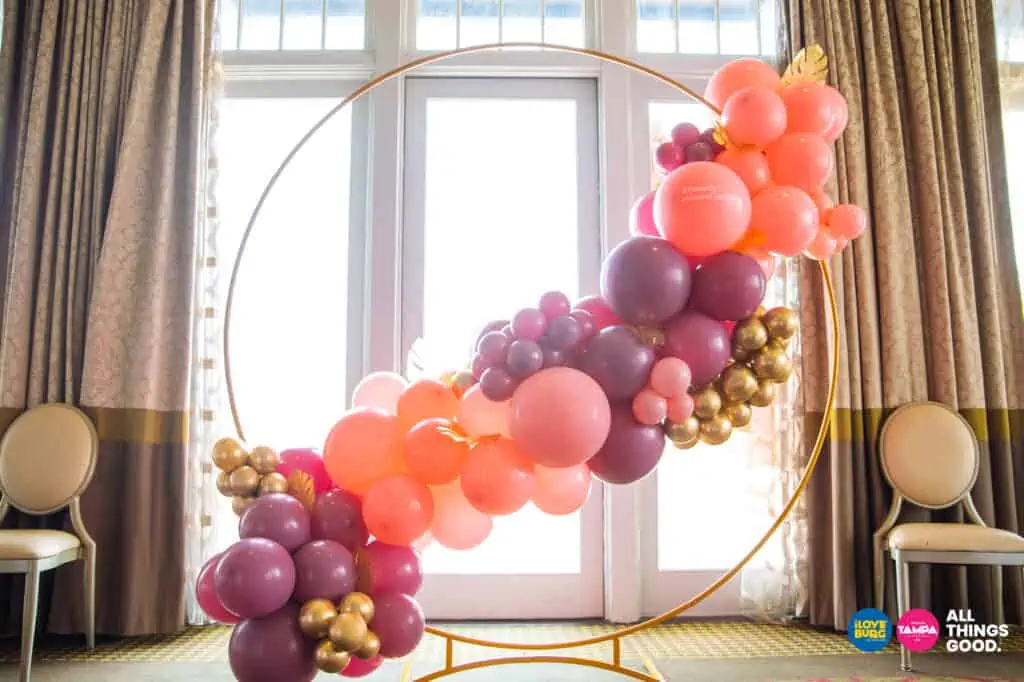 a gold arch decorated with pink and purple and gold balloons