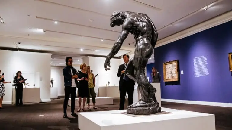 A massive Rodin sculpture stands on a platform in the middle of a room surrounded by other art