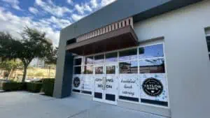 Exterior of a restaurant with tall glass windows. A coming soon sign is posted on the front.