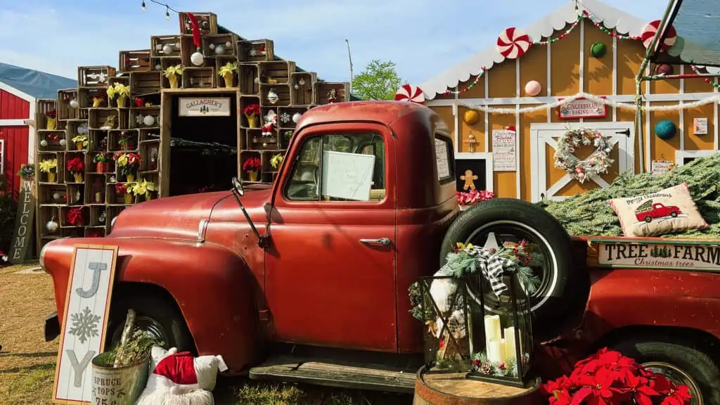 a vintage red truck decorated for Christmas is parked in front of a gingerbread house and other holiday photo ops