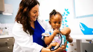 A doctor holding a child with a doll