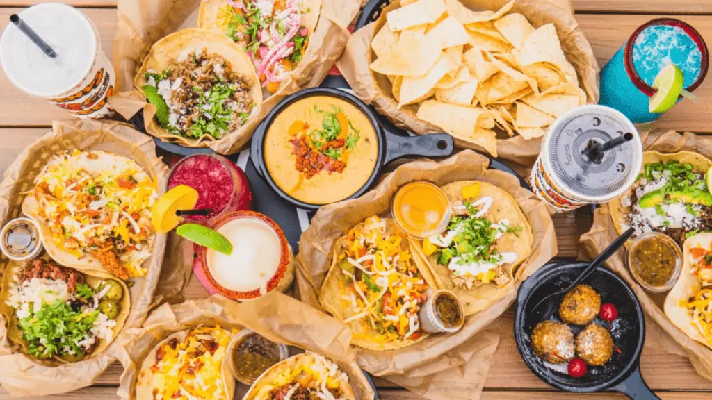 A table of tacos, cheese dip, and drinks