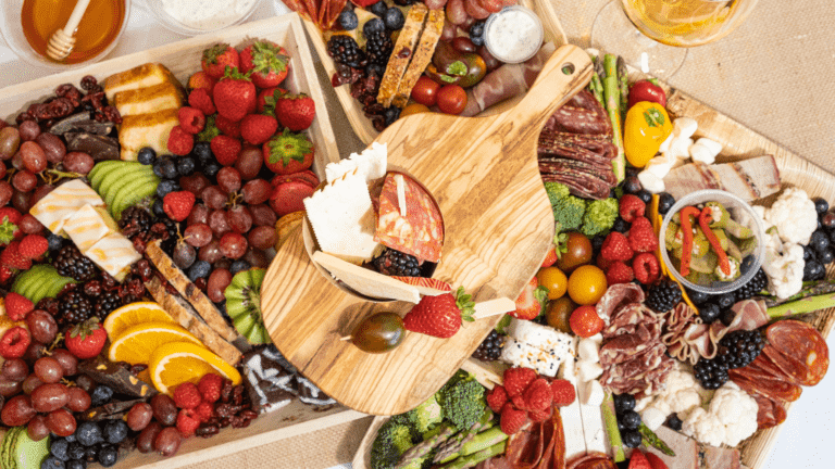 Aerial view of multiple plates of cheese, fruits, and meats.