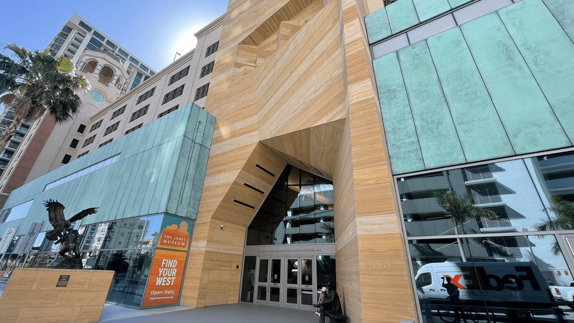 Exterior of a museum with large sculptures out front, a large wooden geometric entrance.