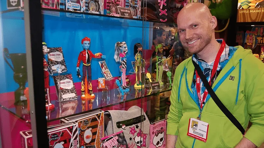 a man stands in front of a glass case with monster figurines displayed.