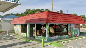 The exterior of Julio's Empanadas - a painted former gas station with a mural depicting Puerto Rico on one side.