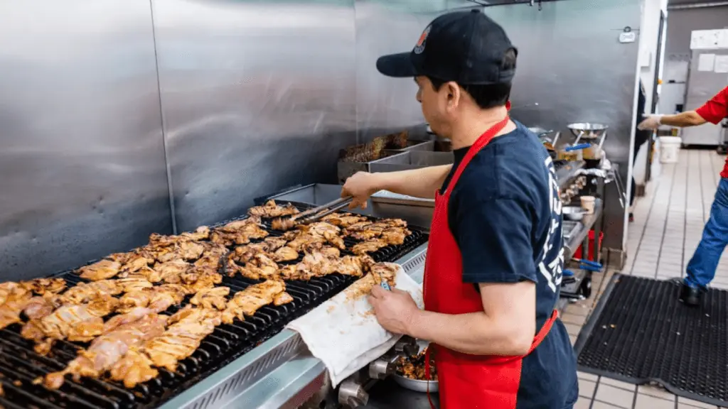 A cook making chicken at Teriyaki Madness