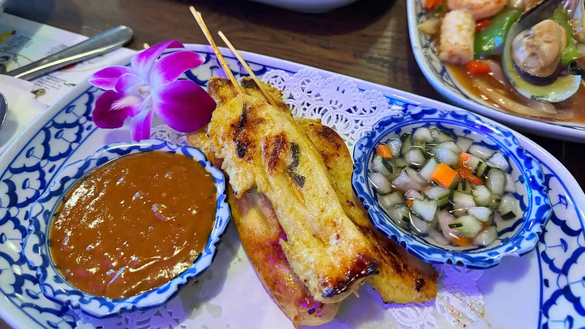 peanut dipping sauce, chicken satay skewers, and a cucumber salad